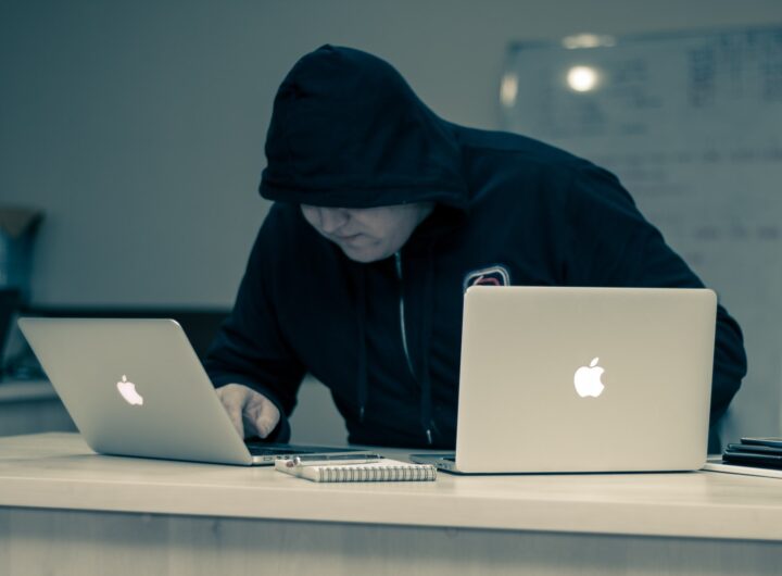 man in black hoodie using macbook