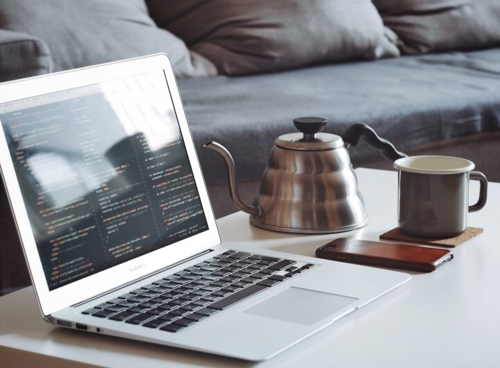 turned on MacBook Air beside black smartphone and black ceramic mug