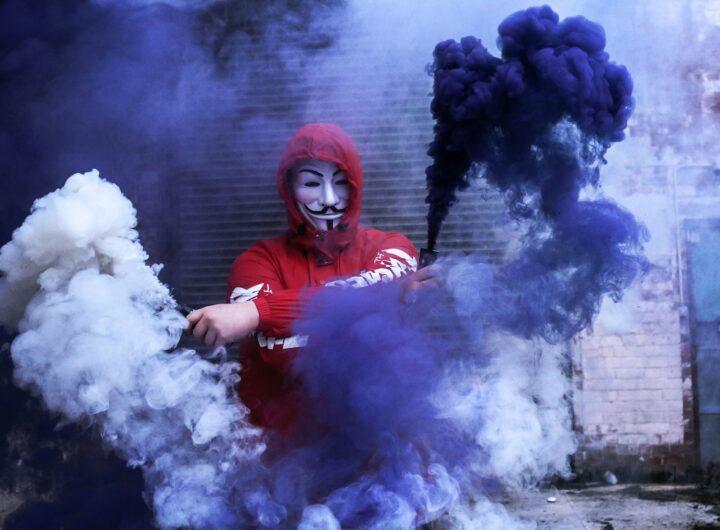 man wearing red hoodie standing near gray wall during daytime photo