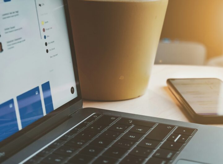 white laptop computer turned on beside brown paper cup