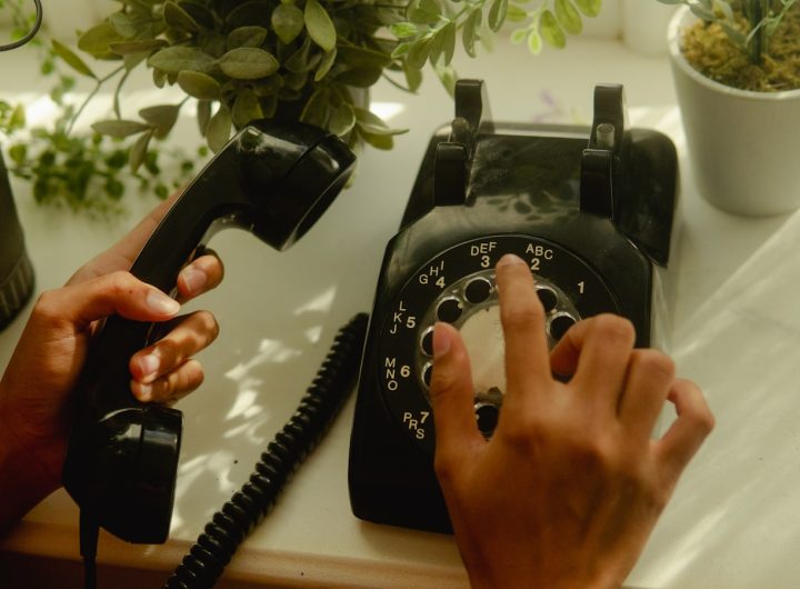 person holding black rotary telephone