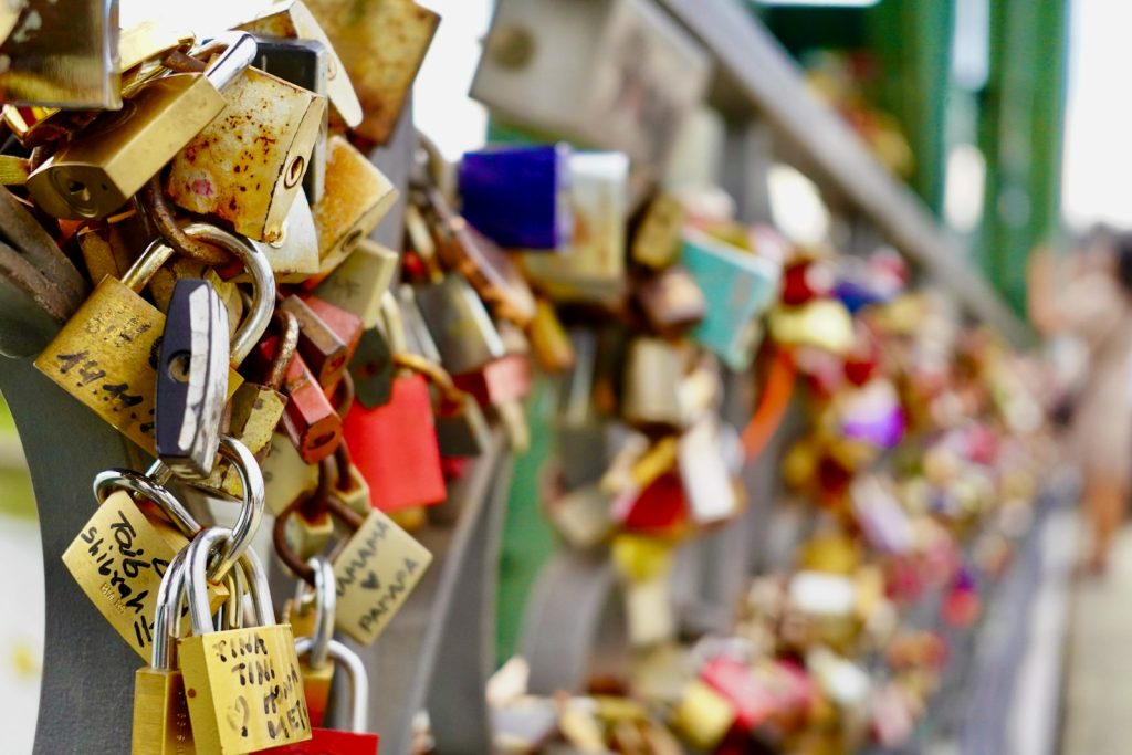 Many padlocks are attached to a fence